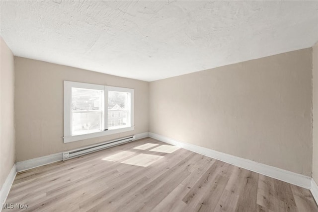 unfurnished room featuring baseboard heating, light wood-type flooring, and a textured ceiling