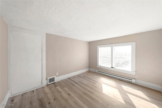 empty room with a baseboard radiator and light hardwood / wood-style flooring