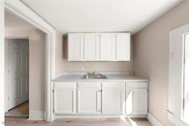 interior space with white cabinets, light wood-type flooring, and sink