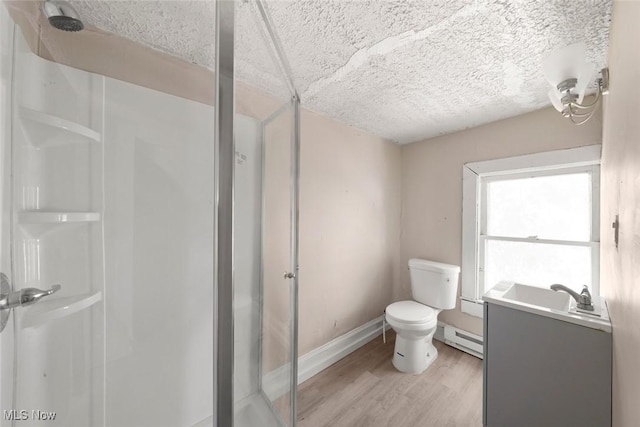 bathroom featuring hardwood / wood-style floors, a baseboard heating unit, an enclosed shower, and vanity