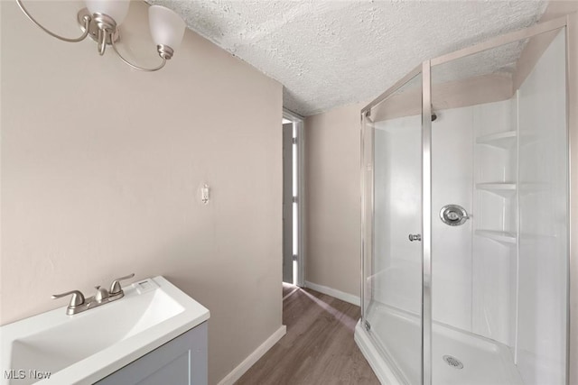 bathroom with wood-type flooring, vanity, a textured ceiling, and walk in shower