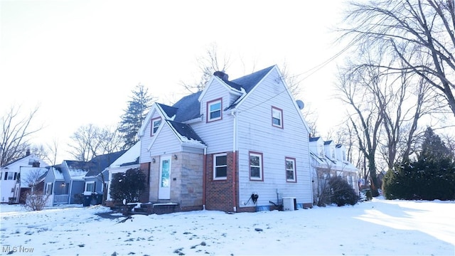 view of front of property featuring stone siding, a chimney, and central AC unit