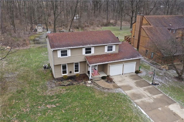 view of front of house with central air condition unit, a shingled roof, concrete driveway, an attached garage, and a front lawn