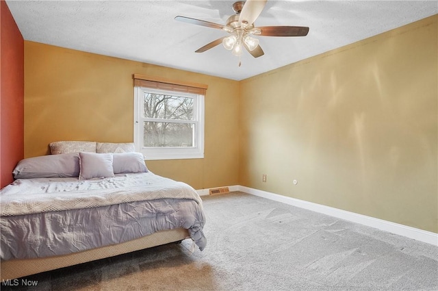 carpeted bedroom featuring ceiling fan and a textured ceiling