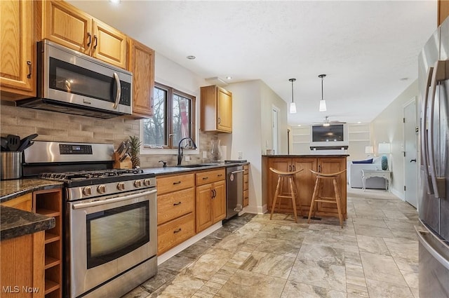 kitchen with kitchen peninsula, hanging light fixtures, stainless steel appliances, sink, and tasteful backsplash