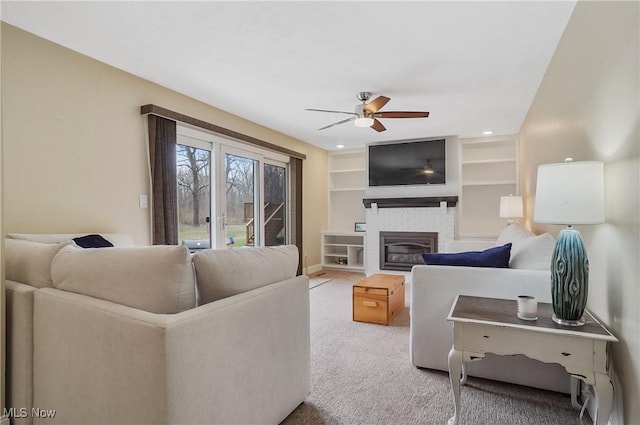 carpeted living room with ceiling fan and built in shelves