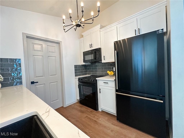 kitchen featuring white cabinetry, hanging light fixtures, black appliances, light hardwood / wood-style floors, and tasteful backsplash