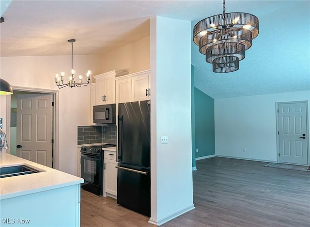 kitchen with white cabinets, hanging light fixtures, black appliances, and a notable chandelier