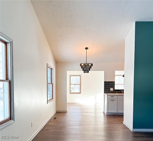 unfurnished dining area with hardwood / wood-style flooring, plenty of natural light, and a chandelier