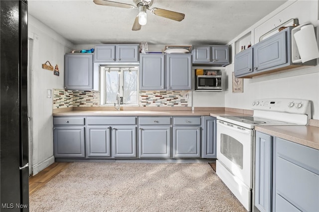 kitchen with gray cabinetry, white electric stove, ceiling fan, light hardwood / wood-style floors, and backsplash