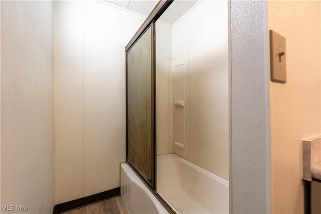 bathroom with hardwood / wood-style flooring and shower / bath combination with glass door