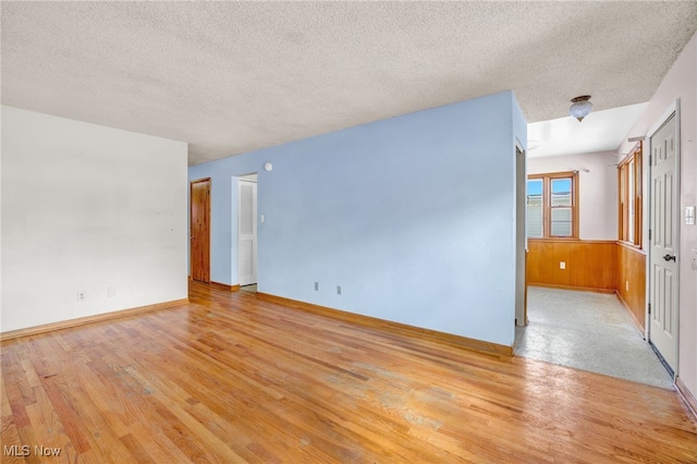 unfurnished room with light wood-type flooring and a textured ceiling