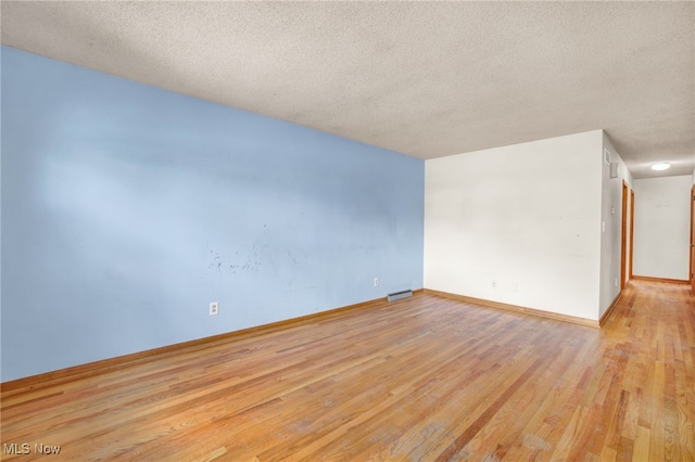 empty room with light hardwood / wood-style flooring and a textured ceiling