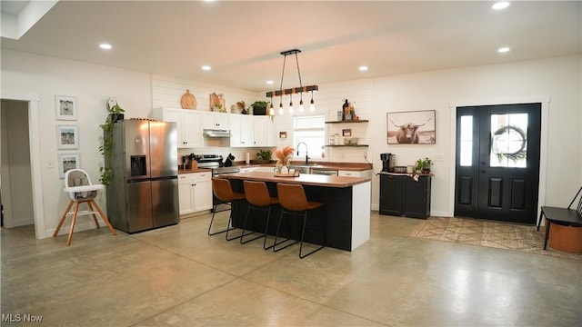 kitchen featuring hanging light fixtures, a breakfast bar, a kitchen island, appliances with stainless steel finishes, and white cabinets