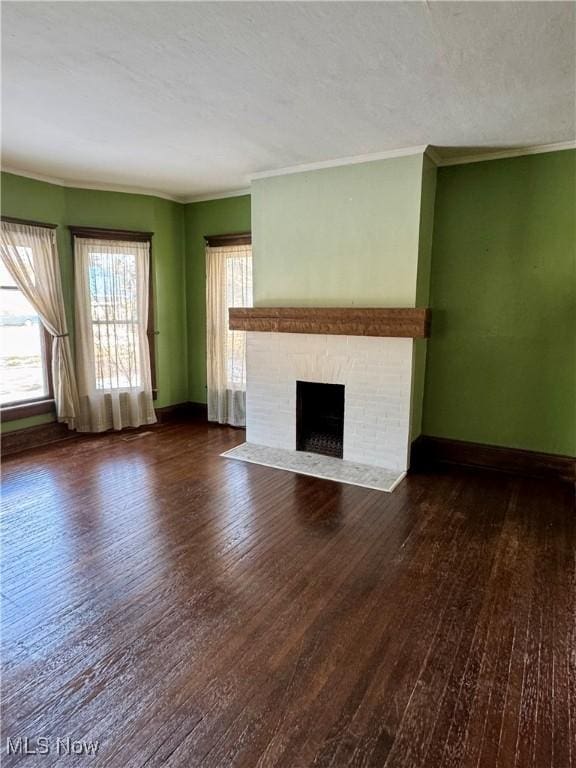 unfurnished living room featuring dark hardwood / wood-style flooring, ornamental molding, a textured ceiling, and a fireplace