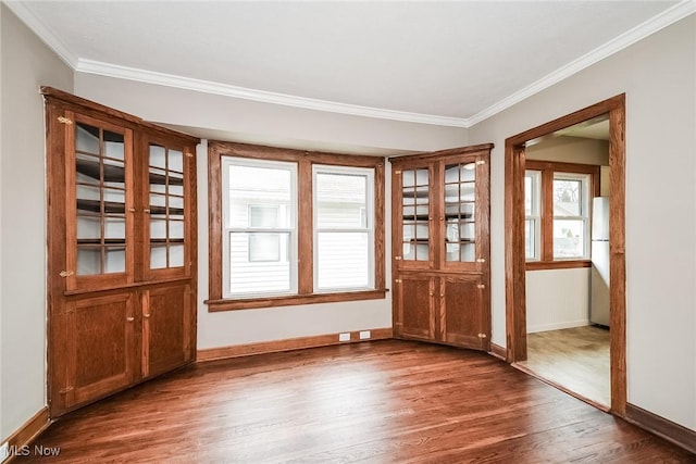 unfurnished dining area featuring dark wood-type flooring and crown molding