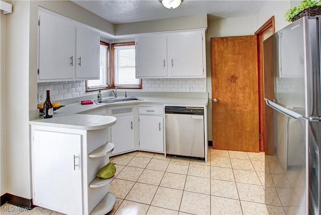 kitchen with a sink, stainless steel appliances, light countertops, and white cabinets