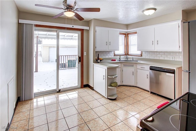 kitchen with light tile patterned floors, white cabinets, light countertops, backsplash, and dishwasher