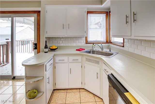 kitchen with light tile patterned flooring, a sink, white cabinets, light countertops, and tasteful backsplash