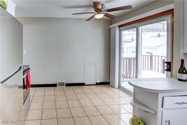 interior space featuring light tile patterned floors, baseboards, visible vents, and a ceiling fan