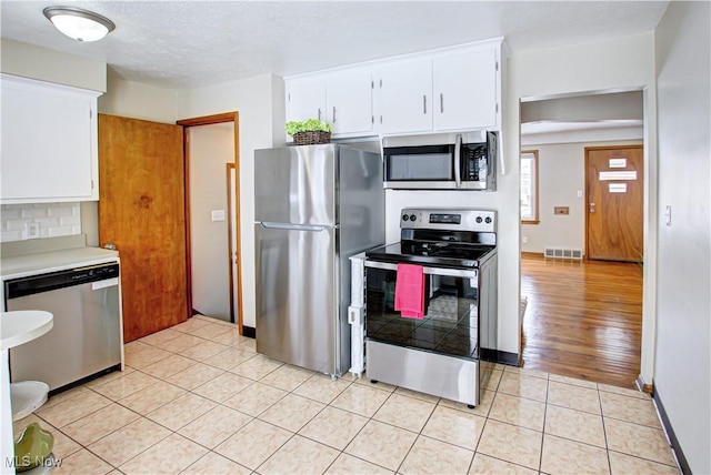 kitchen with light tile patterned floors, light countertops, visible vents, appliances with stainless steel finishes, and white cabinets