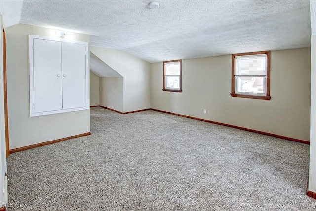 interior space with a textured ceiling, carpet flooring, and baseboards