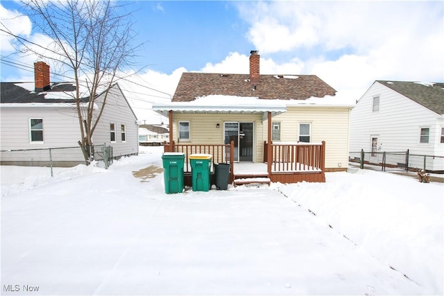 snow covered property featuring a chimney and fence