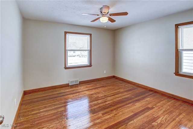 spare room featuring wood finished floors, visible vents, and baseboards