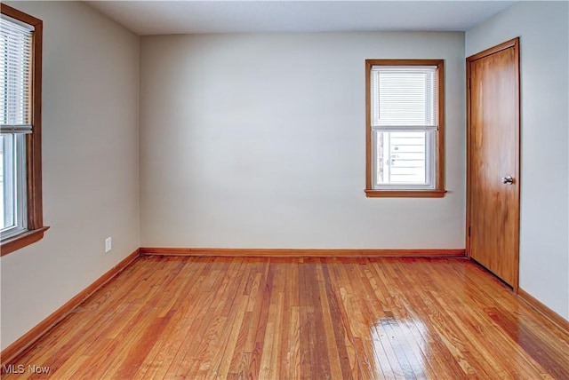 unfurnished room with light wood-type flooring and baseboards