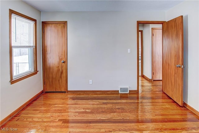 empty room featuring baseboards, visible vents, and light wood finished floors