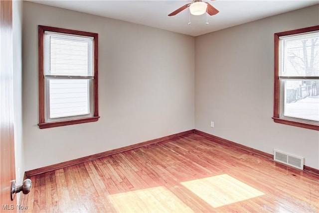 unfurnished room featuring light wood finished floors, baseboards, visible vents, and ceiling fan