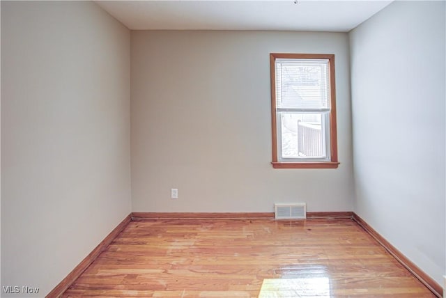 spare room with light wood finished floors, baseboards, and visible vents