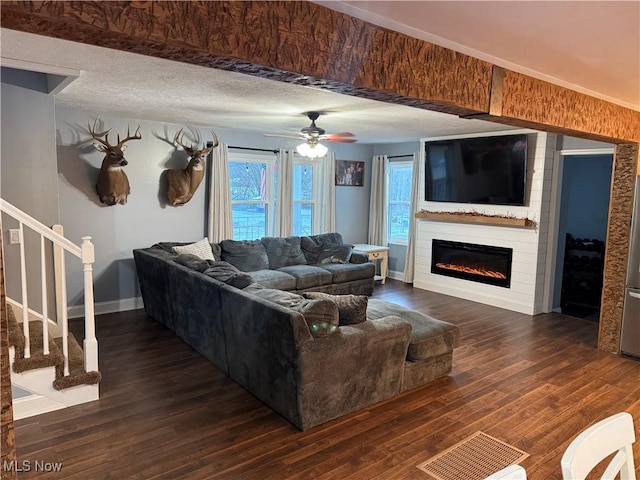 living room featuring a fireplace, dark wood-type flooring, a textured ceiling, and plenty of natural light