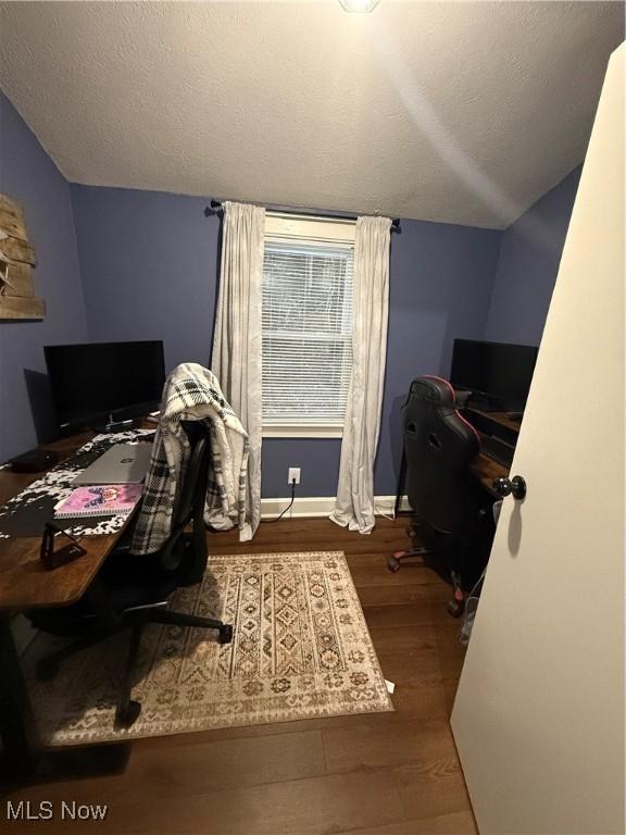 office space with a textured ceiling, vaulted ceiling, and wood-type flooring