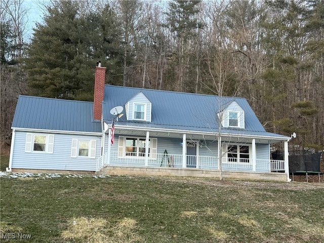 cape cod-style house featuring a trampoline, a front lawn, and a porch