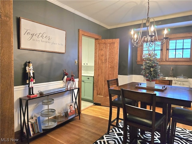 dining area with light hardwood / wood-style floors, crown molding, and a notable chandelier