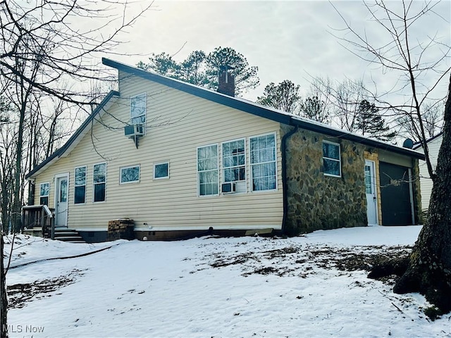 snow covered property with crawl space, stone siding, a chimney, and cooling unit