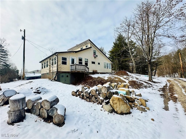 view of snowy exterior with a garage and a deck