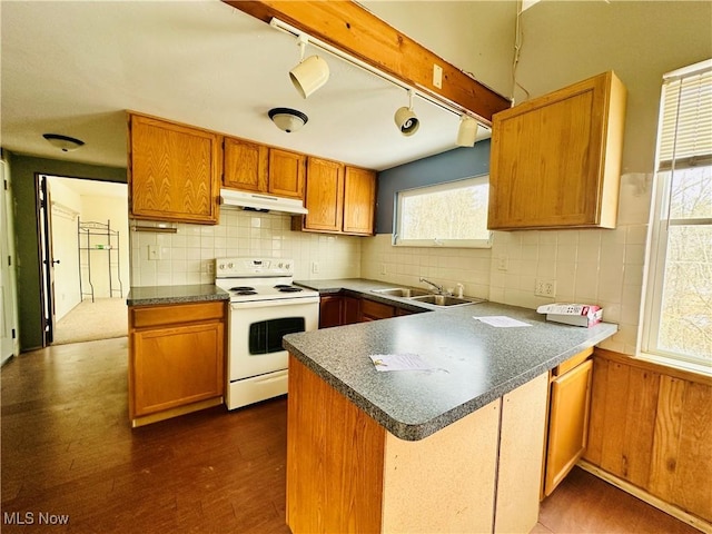 kitchen with brown cabinets, white range with electric cooktop, dark countertops, a sink, and under cabinet range hood