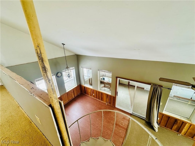 stairway featuring wooden walls and vaulted ceiling