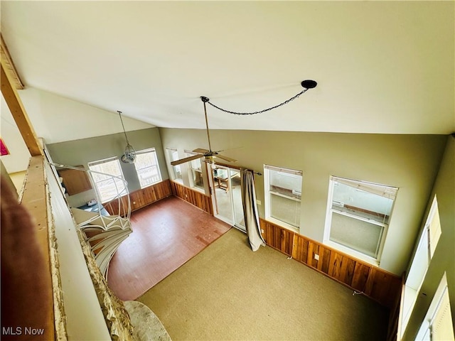 additional living space featuring wooden walls, high vaulted ceiling, a ceiling fan, and light colored carpet