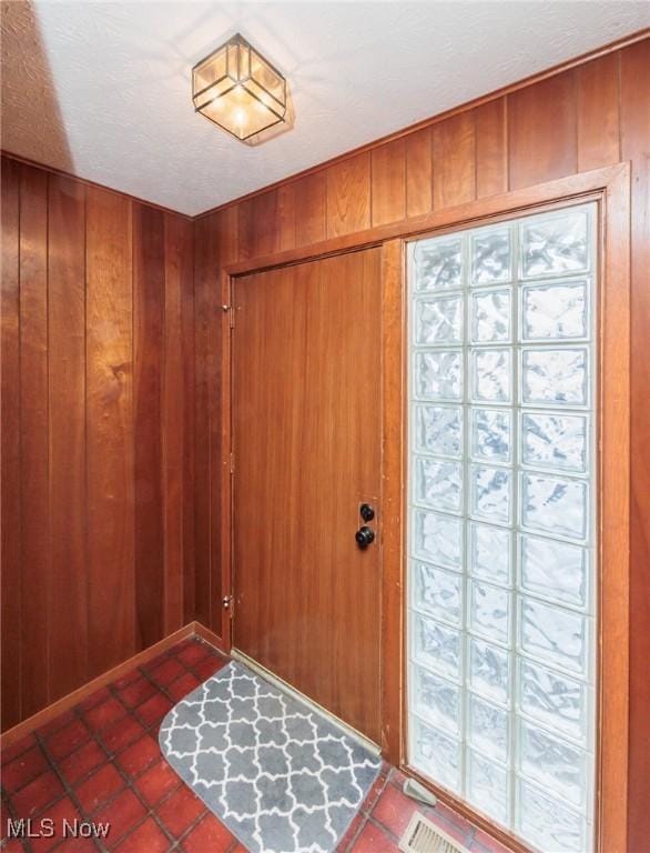 entrance foyer featuring dark tile patterned flooring and wood walls