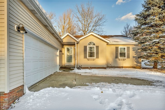 snow covered property entrance with a garage