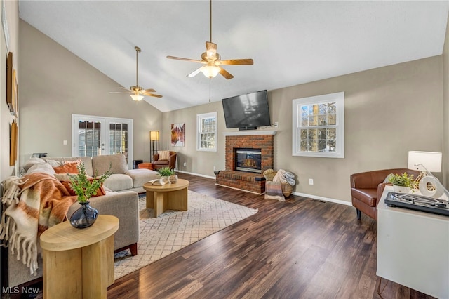 living room with a brick fireplace, ceiling fan, french doors, and dark wood-type flooring