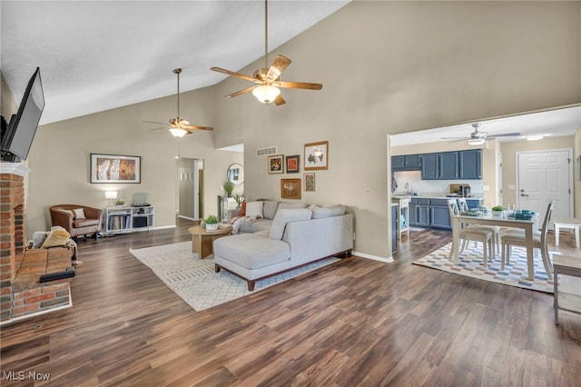 living room featuring high vaulted ceiling, a brick fireplace, and dark hardwood / wood-style floors