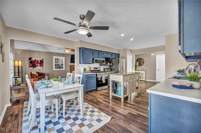 kitchen featuring blue cabinetry, stainless steel appliances, dark hardwood / wood-style flooring, a center island, and a textured ceiling