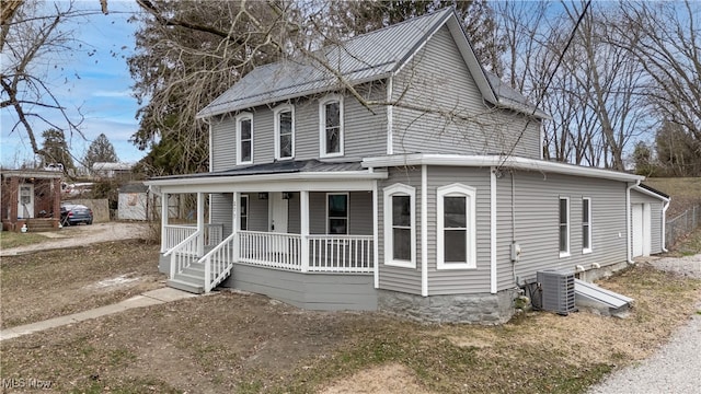 view of front of house with central AC unit, a garage, and a porch