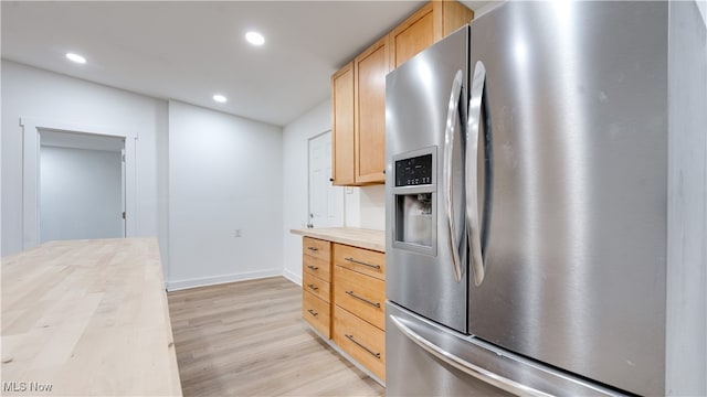 kitchen with light wood-type flooring, butcher block countertops, light brown cabinetry, and stainless steel fridge with ice dispenser