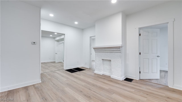 unfurnished living room with a fireplace and light wood-type flooring