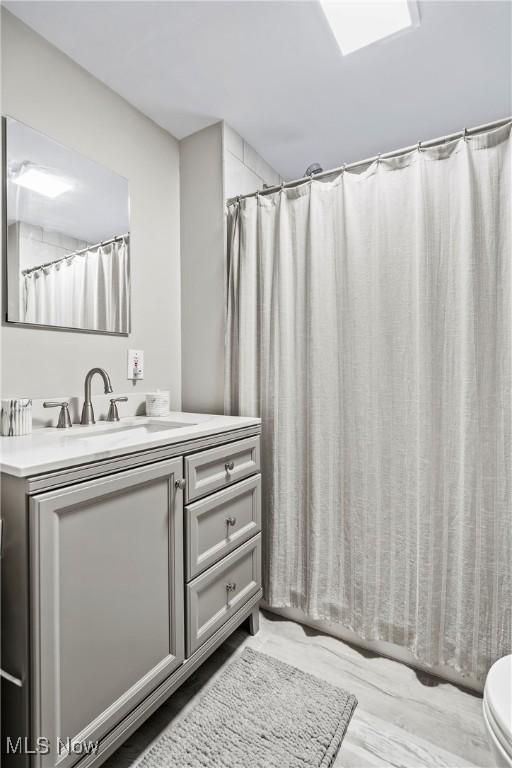 bathroom featuring toilet, a shower with shower curtain, and vanity